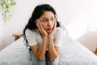 A person holding their face with a stressed look.